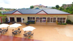 A building with a fitness center, a salon, and outdoor seating with umbrellas. - Cofkans Hotel (Obuasi)