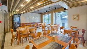 A restaurant with wooden tables and chairs, a bar area, and large windows offering a view of the outdoors. - Alyssa Da Nang Hotel (Da Nang)