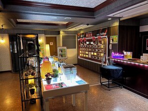 A hotel lobby with a reception desk, a display of local products, and a wall with framed pictures. - HOTEL Gallery - Adults Only (Kobe)