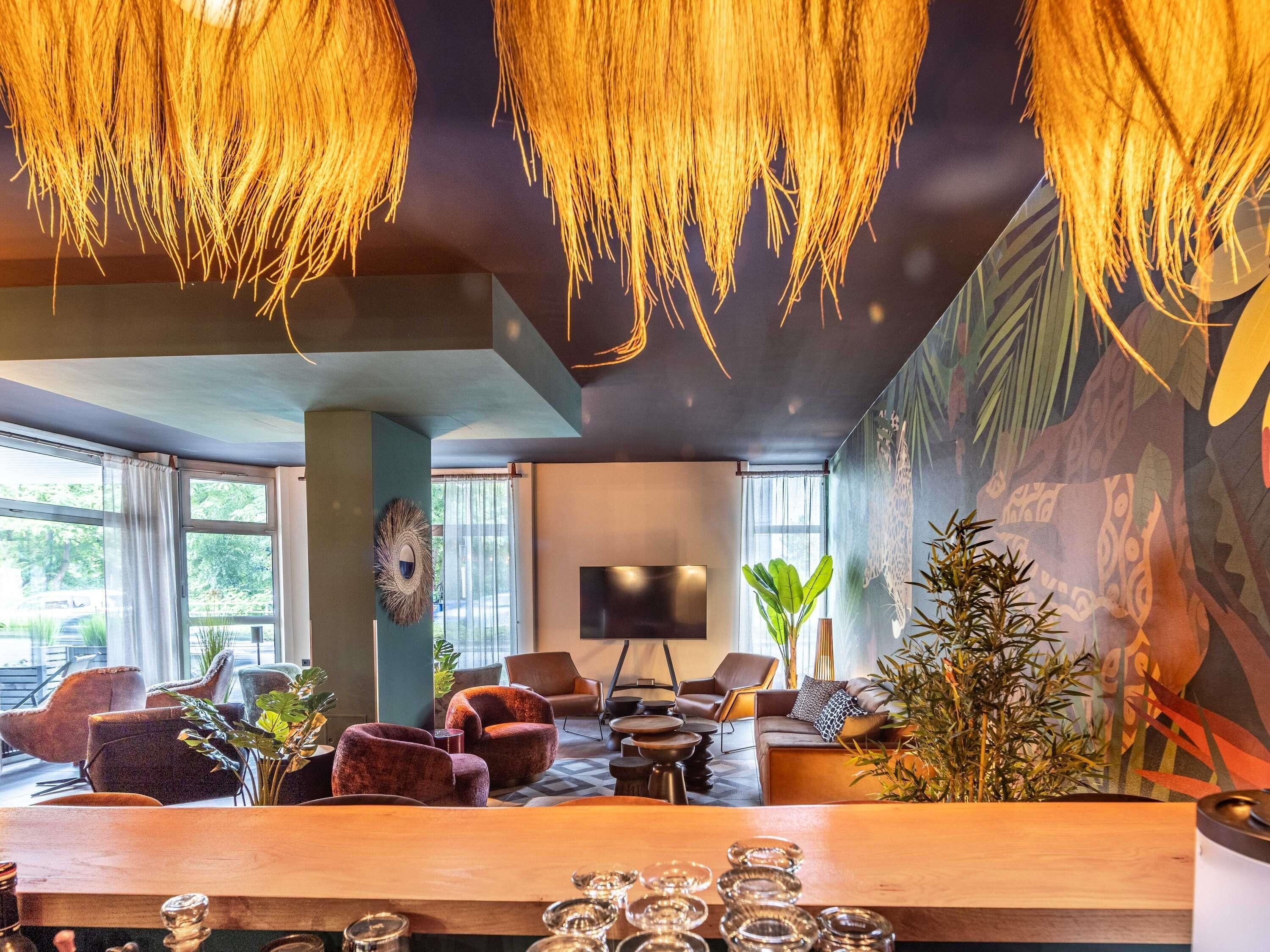A modern lounge with a large wooden table, comfortable seating, a flat-screen TV, and a mural on the wall.