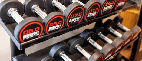 A set of dumbbells with weight markings on a rack.