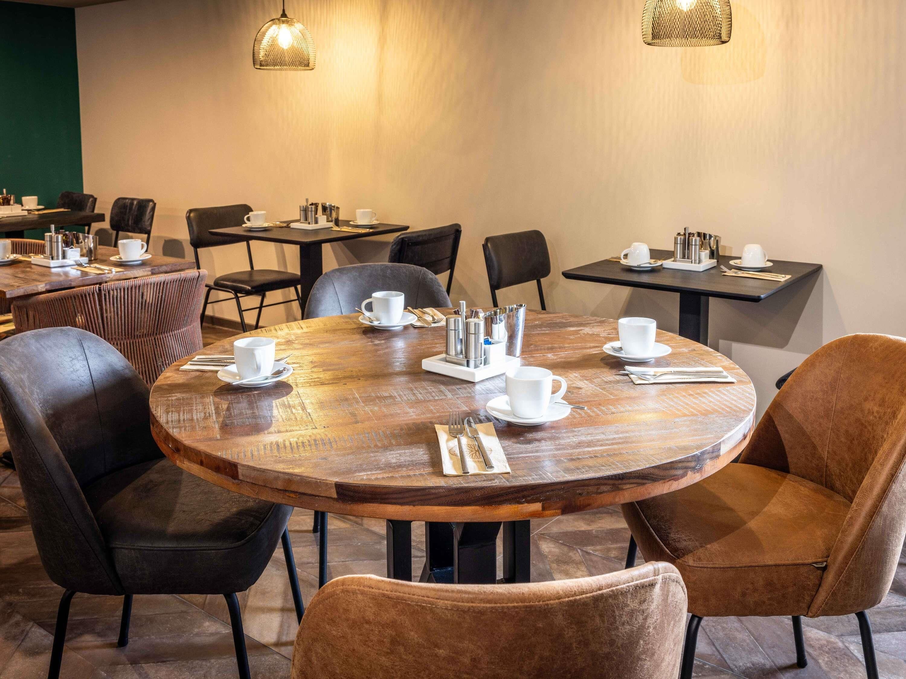 A conference room with round tables, chairs, and coffee cups.