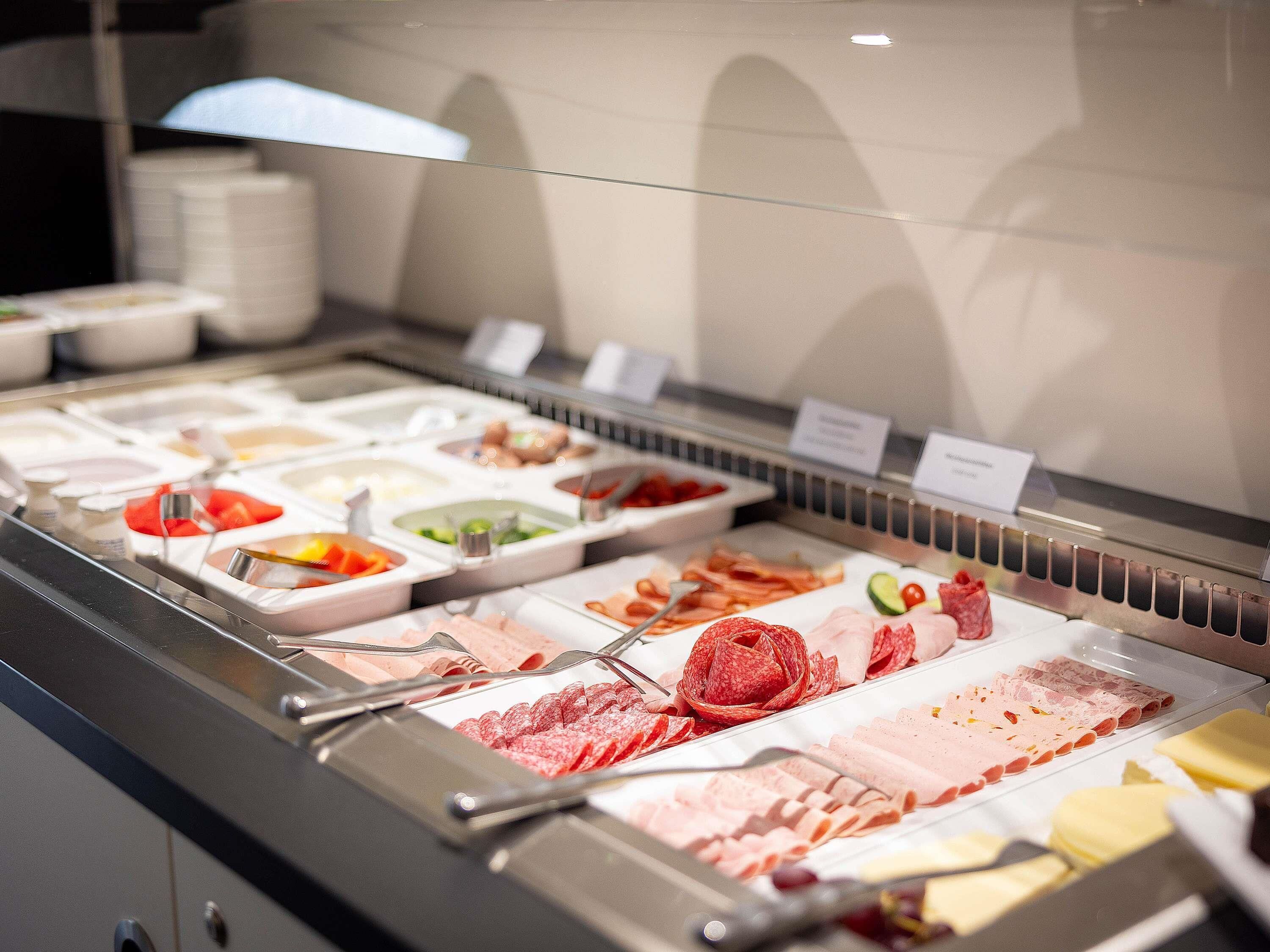 A buffet with various food items including meats, cheeses, and vegetables.