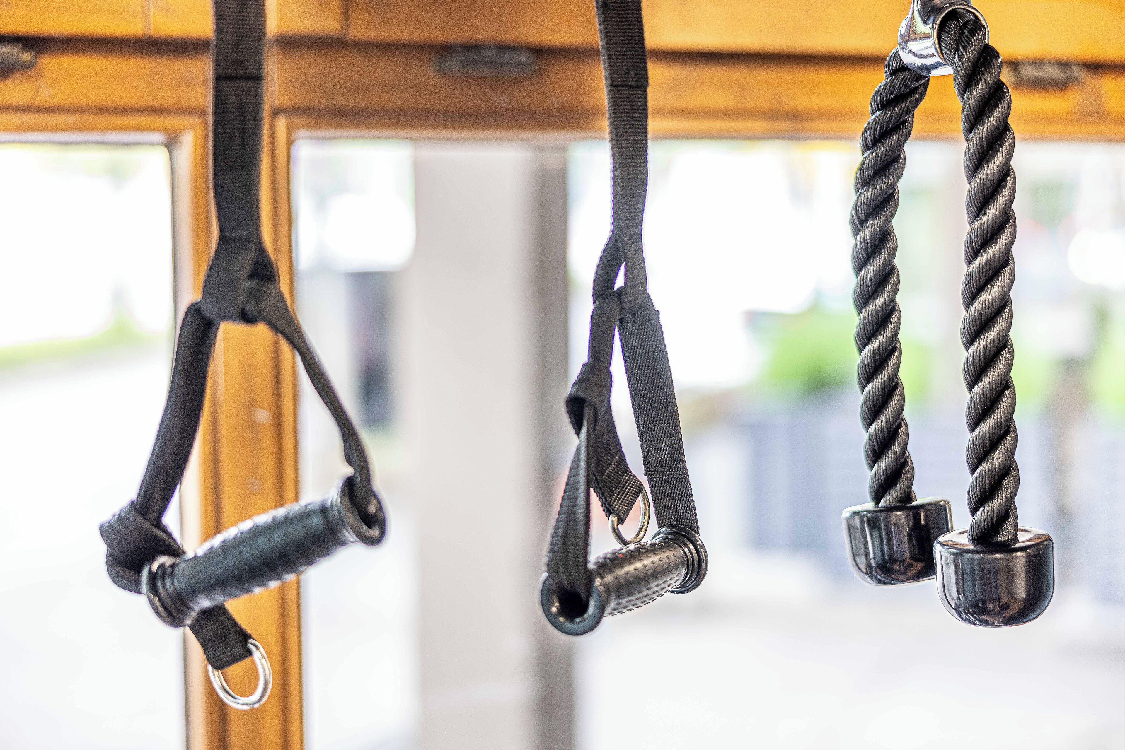 Equipamento de exercícios, incluindo um cabo e um peso, pendurados no teto.