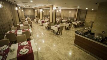 A spacious dining area with multiple tables set for dining, a central bar area, and a polished marble floor.