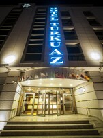 Entrada de un hotel con un llamativo letrero iluminado que dice "HOTEL TURKU AZ".