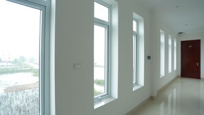 Um corredor com grandes janelas, uma porta e um interruptor de luz na parede.