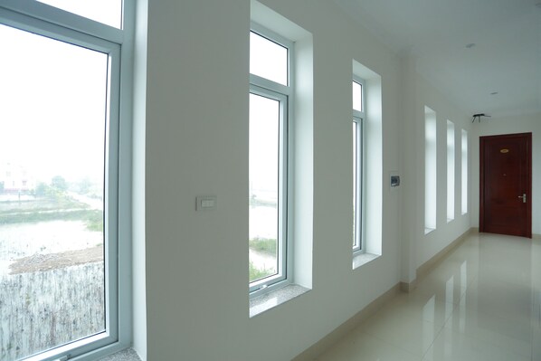 A corridor with large windows, a door, and a light switch on the wall.