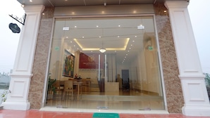 Entrada de hotel com balcão de recepção, um quadro e uma parede de mármore.