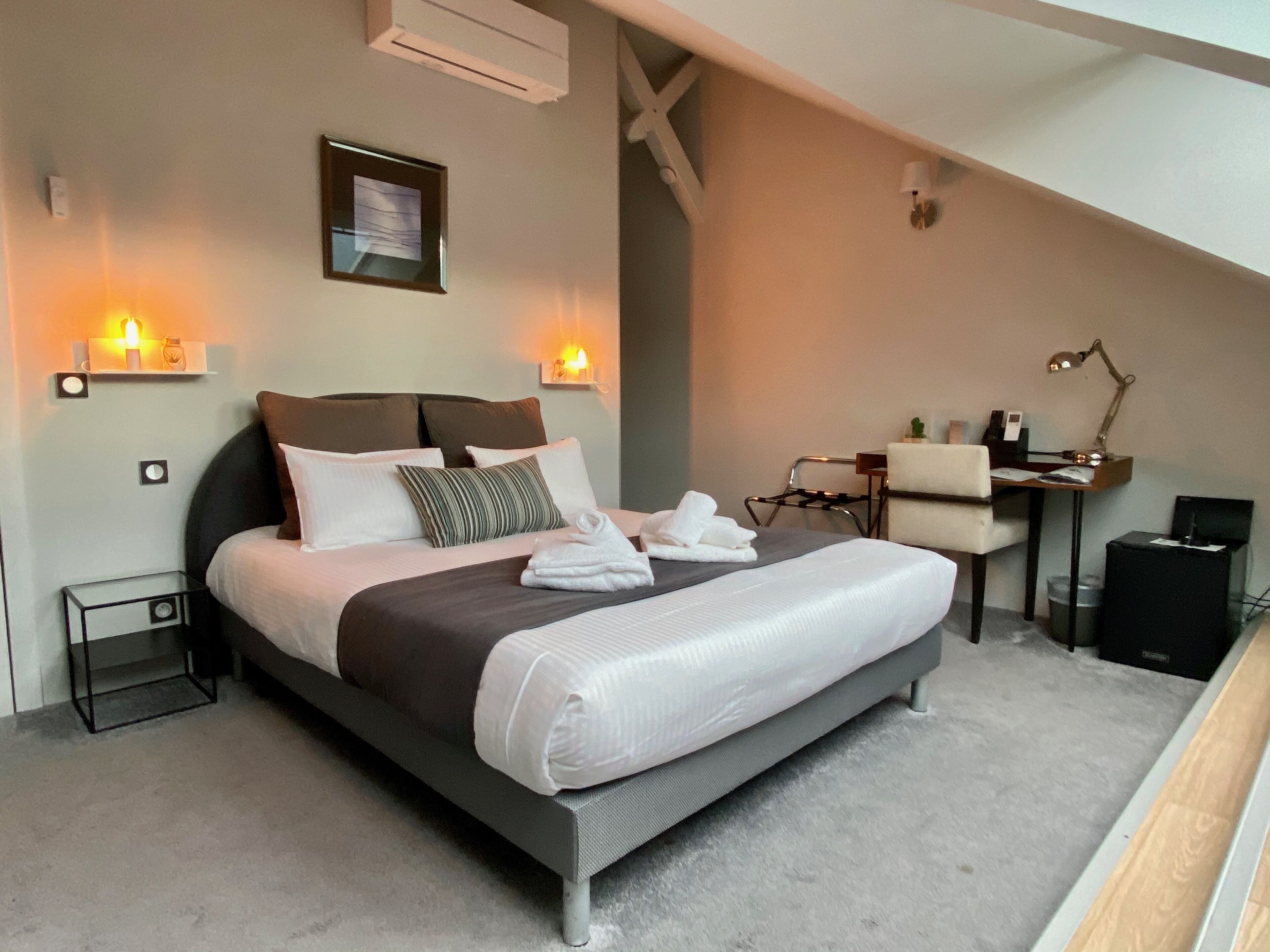 Une chambre moderne avec un grand lit, des lampes de chevet, un bureau et une chaise.