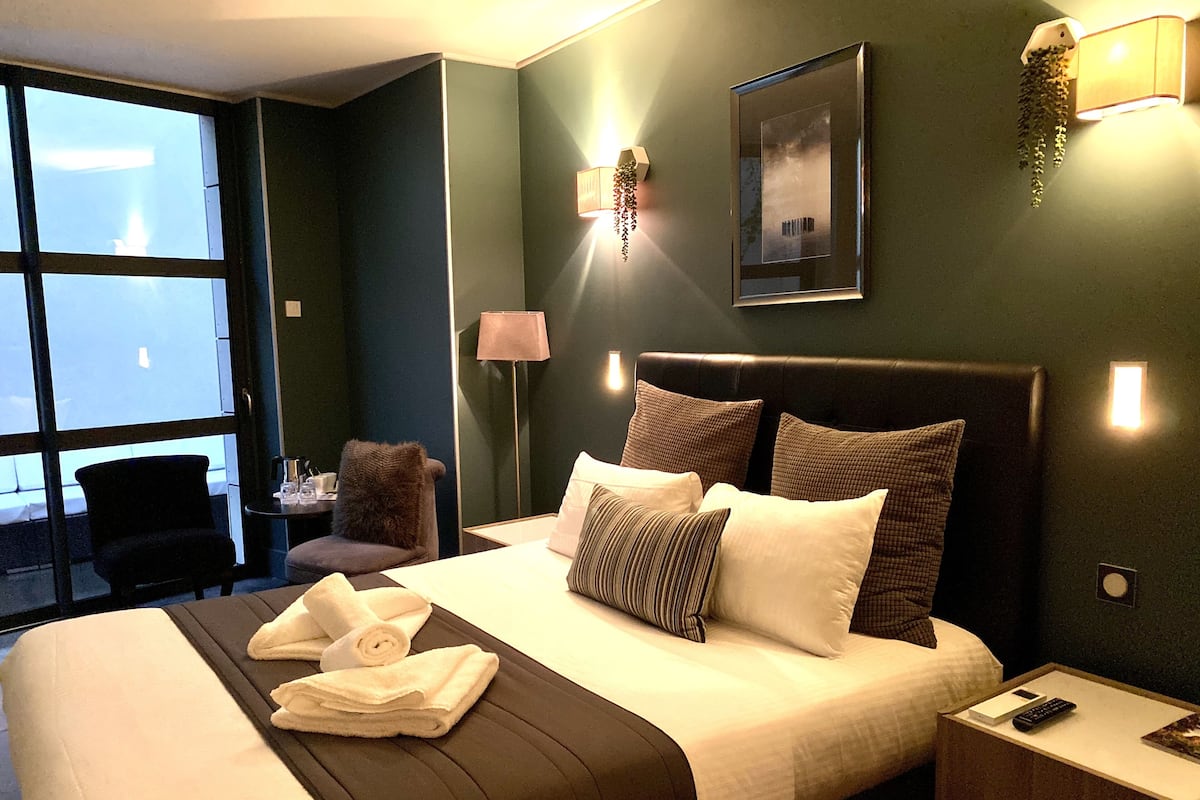 Een hotelkamer met een groot bed, een stoel, een bureau en een raam.
