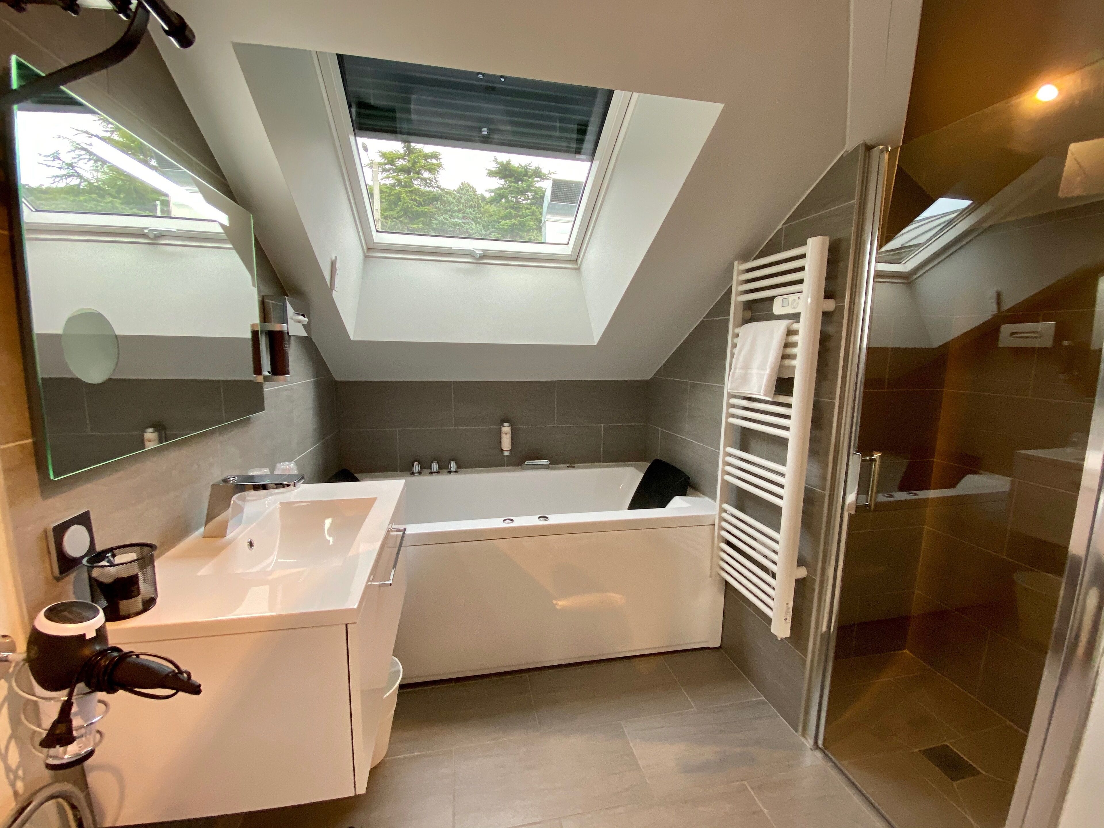 Un baño moderno con tragaluz, bañera, ducha y tocador con espejo.