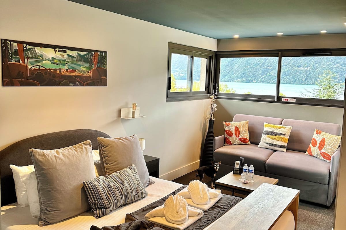 Een moderne hotelkamer met een groot bed, een bank, een houten bijzettafeltje en een schilderij aan de muur.