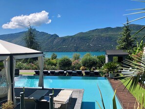 A pool with lounge chairs and a view of mountains and a lake. - Les suites du lac (Aix-les-Bains)