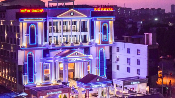 A hotel with a classical facade, neon signage, and a prominent dome structure. - RG Royal Hotel and Convention (Bengaluru)