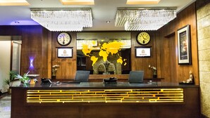A reception desk with two clocks, a world map, and framed certificates. - RG Royal Hotel and Convention (Bengaluru)