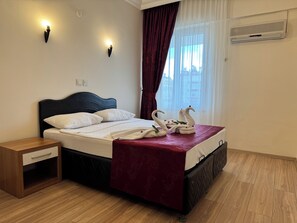 Ein Hotelzimmer mit Bett, Nachttisch, einer roten Bettdecke und einer dekorativen Schwanen-Handtuch-Arrangement.