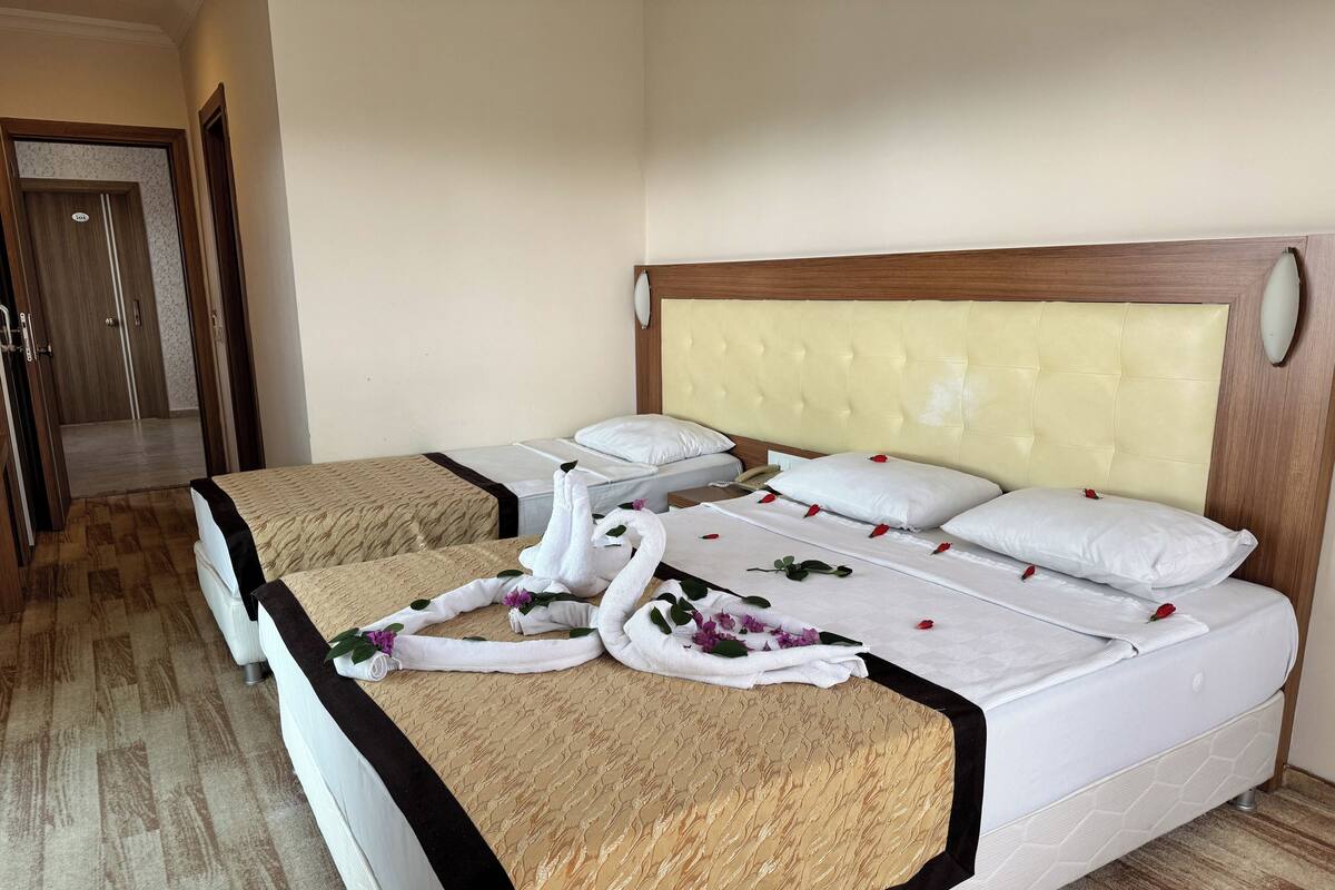 A hotel room with two beds, a wooden headboard, a bedside phone, and a door leading to a bathroom.