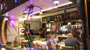 A restaurant with tables and chairs, a bar area, and decorative elements like plants and lanterns. - Mitos App & Hotel (Alanya)