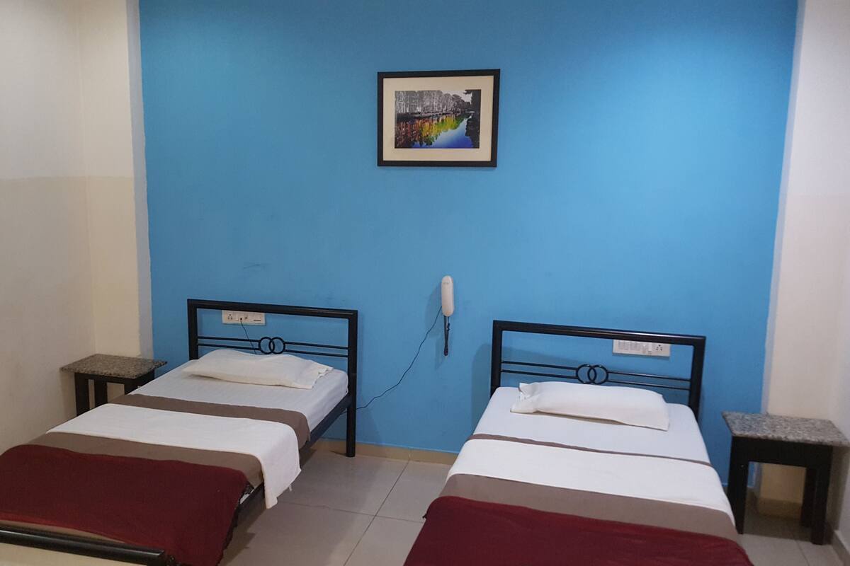 A room with two beds, a blue wall, and a framed picture.