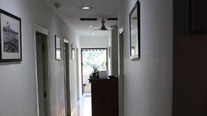 A long, narrow hallway with white walls and tiled flooring. - Deccan Comforts (Hyderabad)