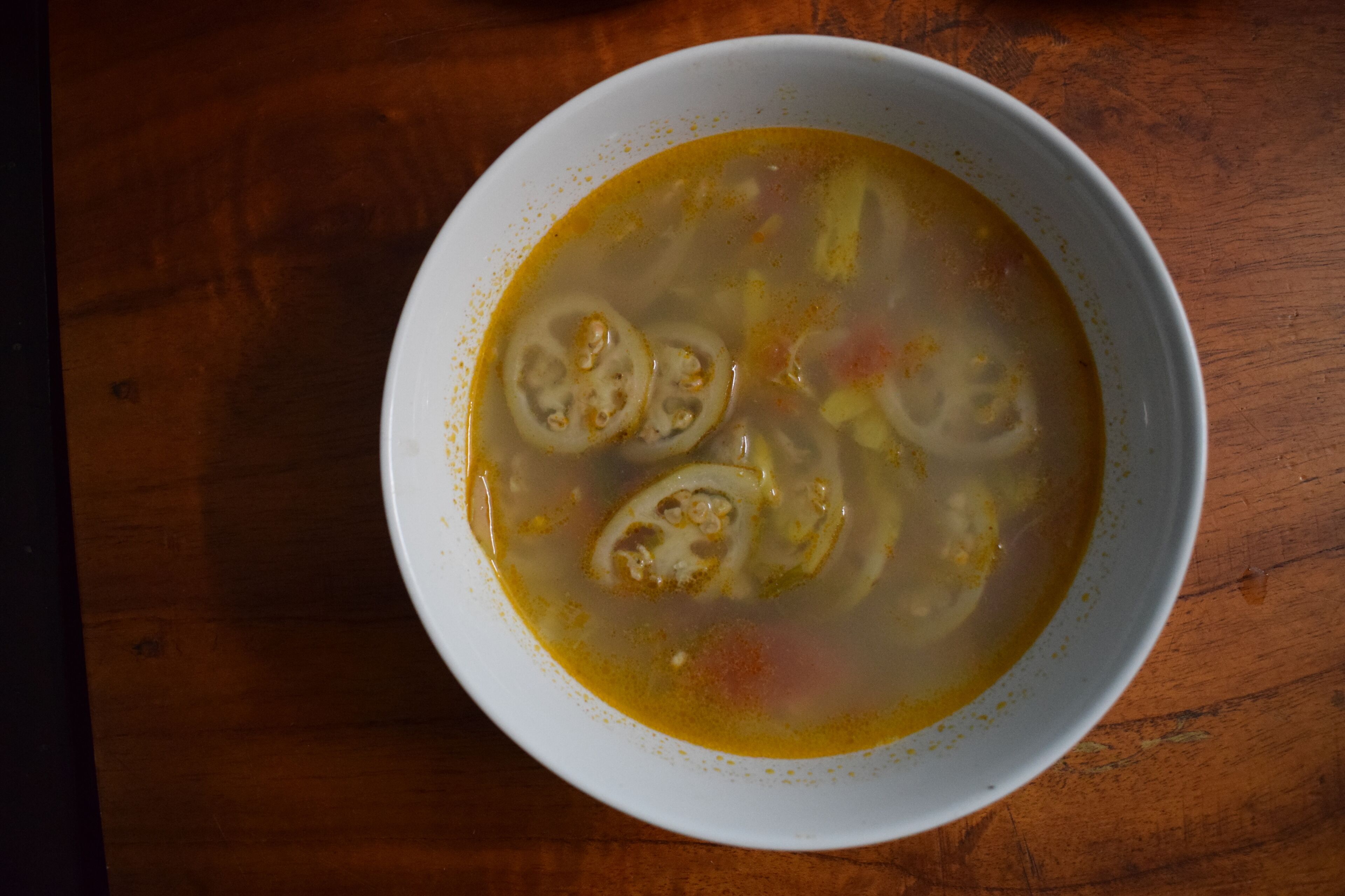 A bowl of soup on a wooden table.