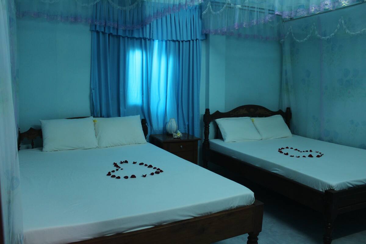 A bedroom with two single beds, each with a heart-shaped arrangement of rose petals on the bedspread.