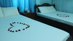 Two beds with white linens and rose petals arranged on the beds. - Island Smiles Homestay (Da Nang)