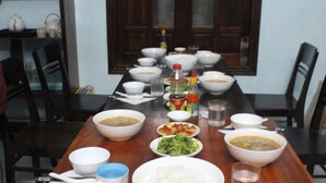 A dining table set with various dishes, including bowls of soup and rice, and condiments. - Island Smiles Homestay (Da Nang)