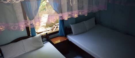 Un dormitorio con dos camas, una mesita de noche y un ventanal con cortinas.