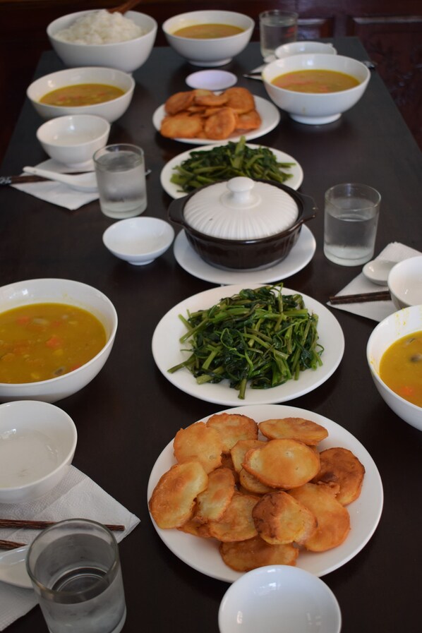 A table set with various dishes including bowls of soup, plates of vegetables, and fried items.