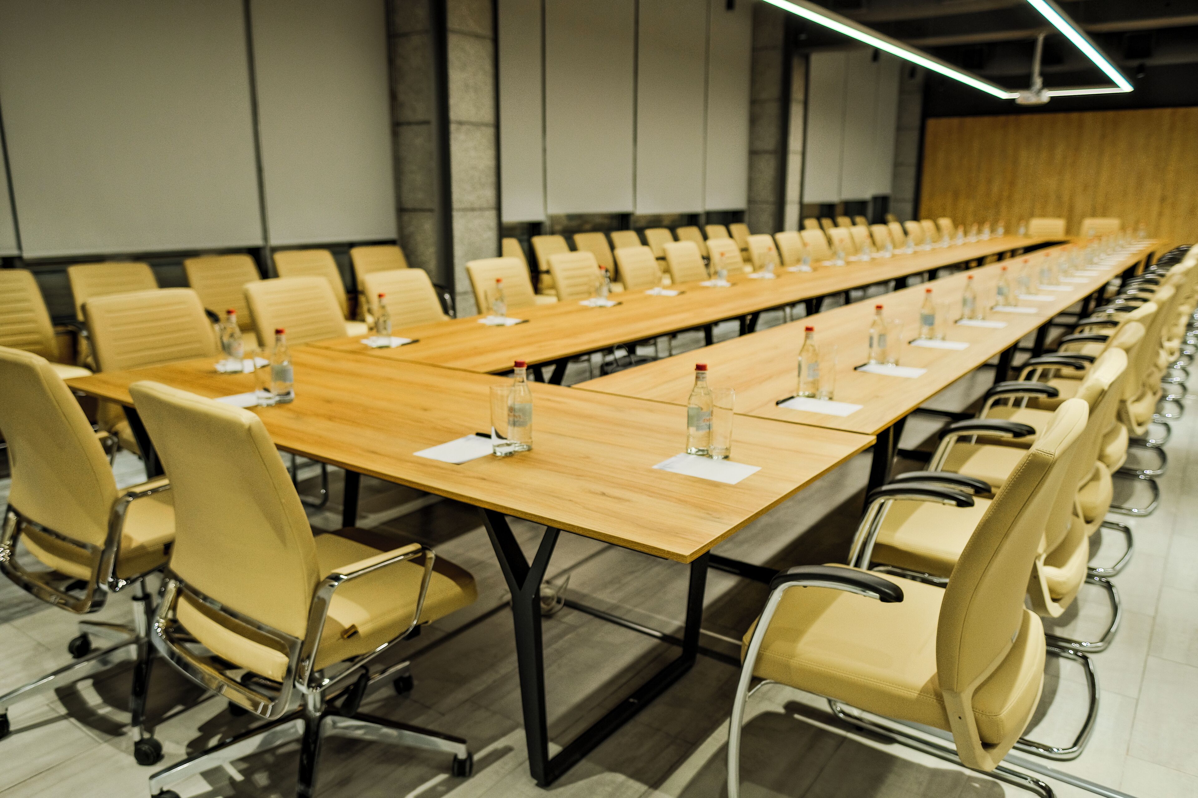 Une salle de conférence avec une longue table, de nombreuses chaises et des bouteilles d’eau posées sur la table.