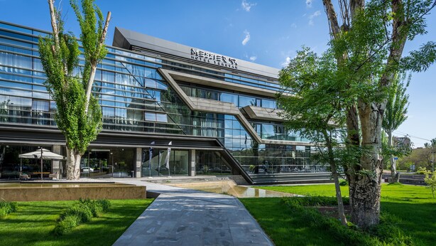 A modern hotel with a glass facade, outdoor seating, and a landscaped entrance. - Messier 53 Hotel Yerevan (Yerevan)
