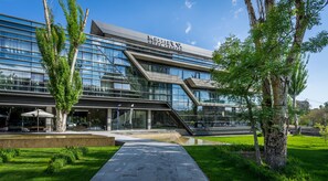 A modern hotel with a glass facade, outdoor seating, and a landscaped entrance. - Messier 53 Hotel Yerevan (Yerevan)