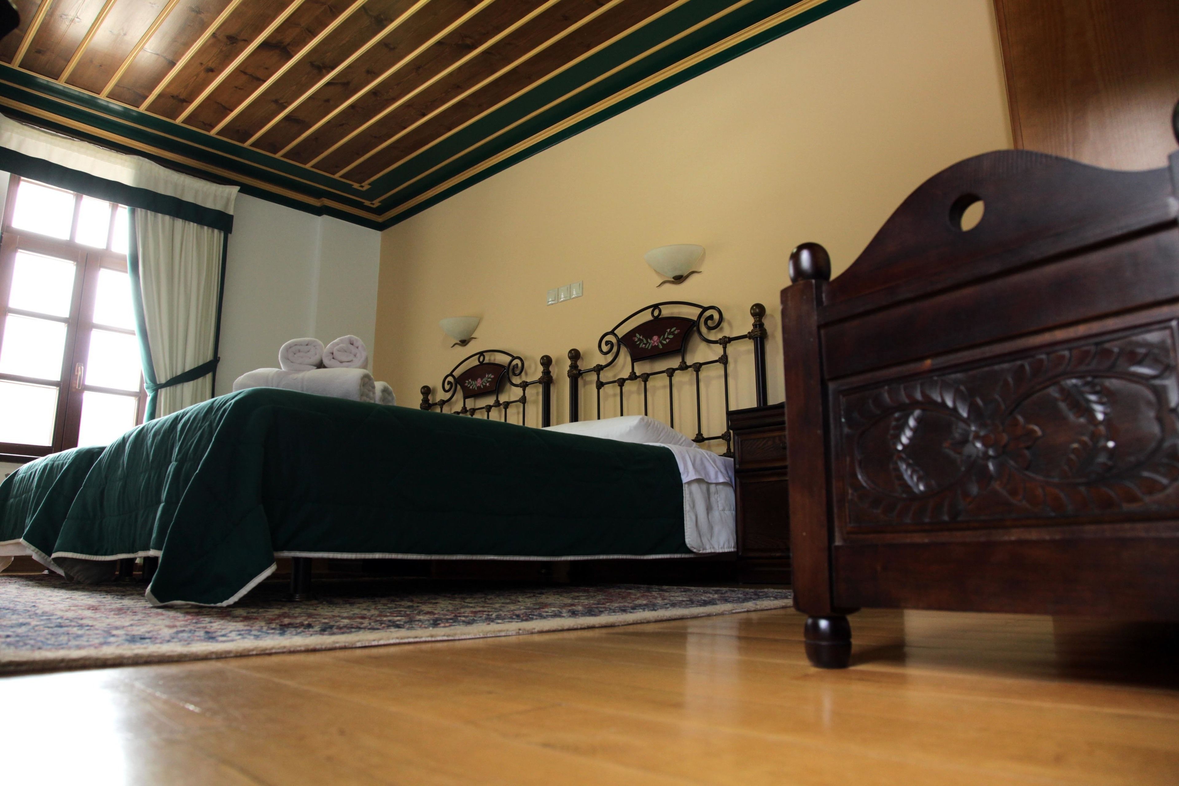 Un dormitorio con una cama de madera, una mesita de noche y una ventana con cortinas.