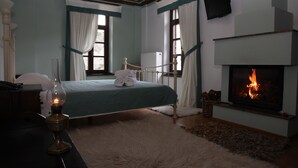 Une chambre à coucher avec un lit, une cheminée et un bureau avec une lampe.