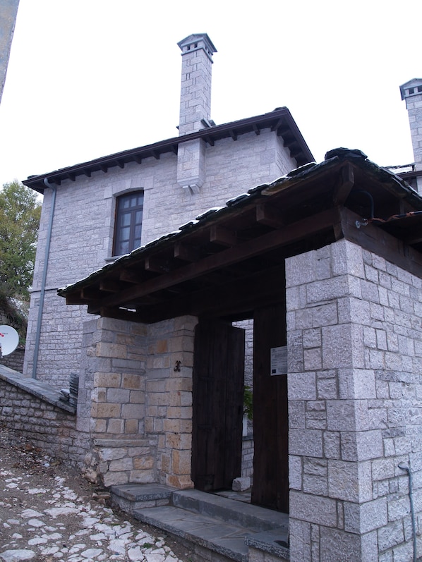 Un edificio de piedra con puerta de madera y un pequeño porche.
