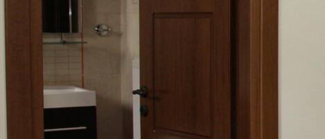 A wooden door leading to a bathroom with a white sink and a mirror.