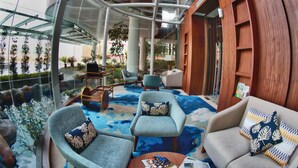 Un espace intérieur moderne doté de coins salon, d’une table centrale et d’un élément décoratif aquatique.