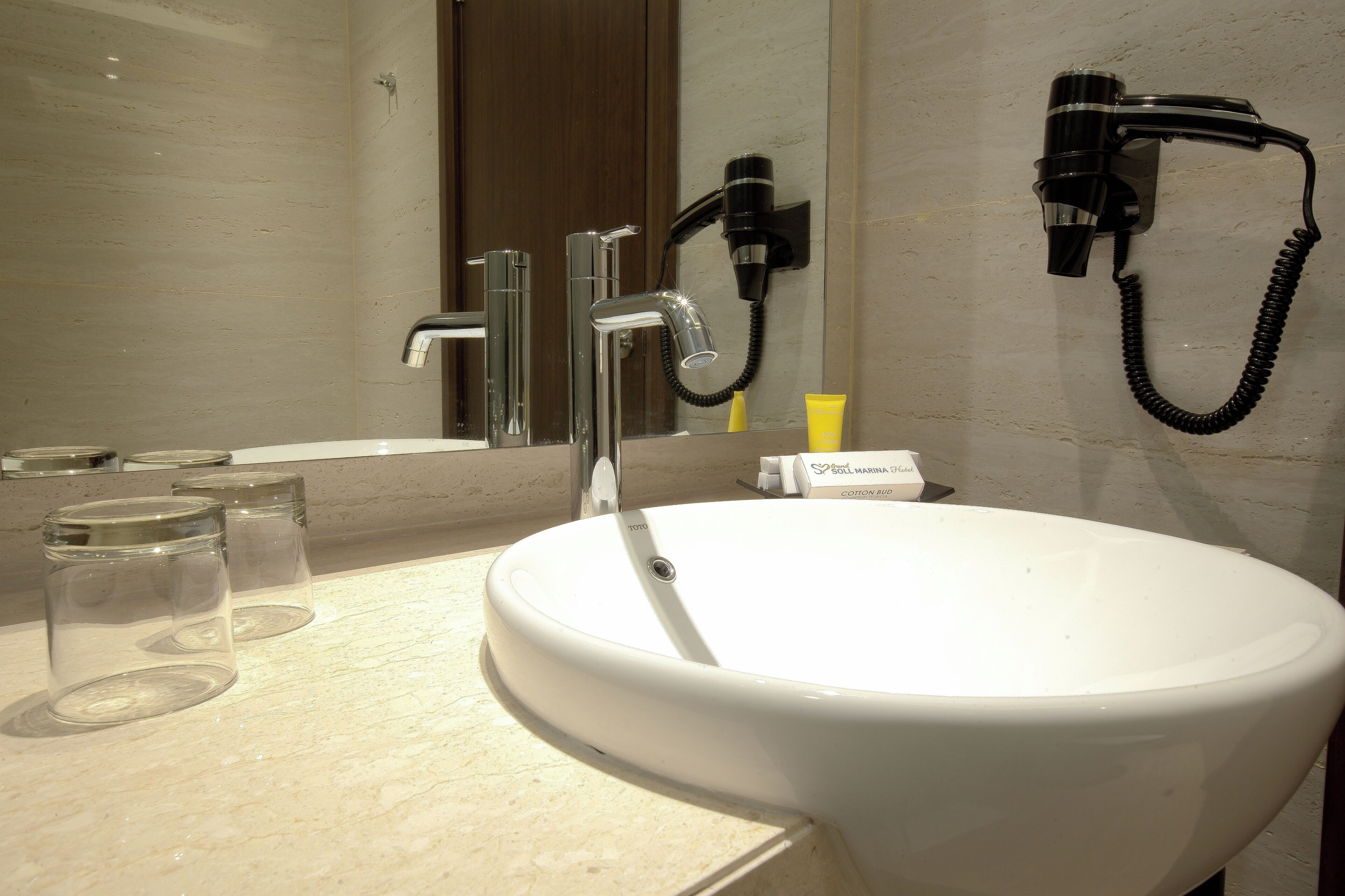 A bathroom with a white sink, two faucets, a hairdryer, and a mirror.