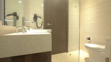 A modern bathroom with a marble sink, a handheld showerhead, and a toilet.