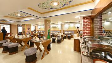Restaurante com mesas e bancos de madeira, balcões de buffet e design decorativo no teto.