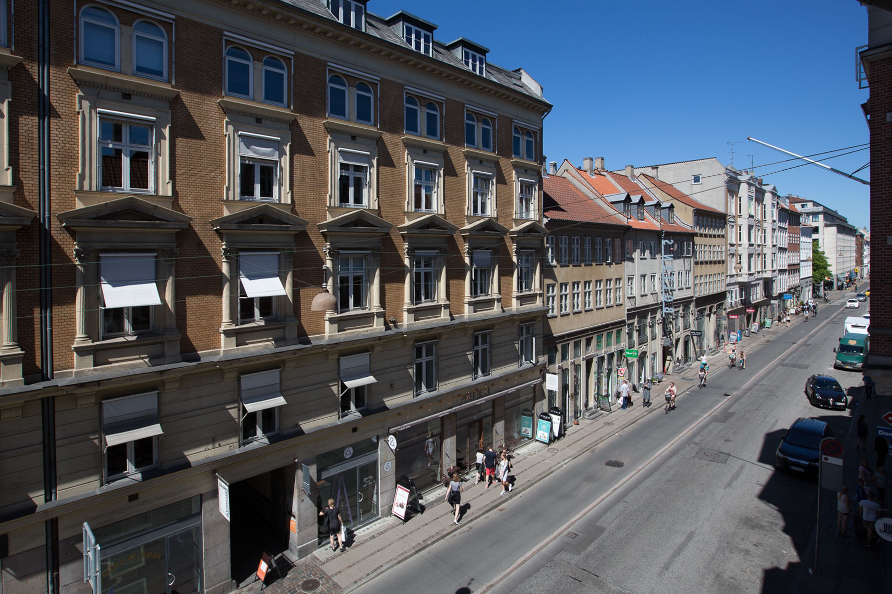 A multi-story building with a row of ground-floor shops and a street in front.