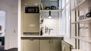A compact kitchen with a microwave, coffee maker, and a window above the sink.