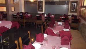 A restaurant with tables set for dining, featuring a checkered tablecloth and red napkins. - Hotel Ravikant (Pune)