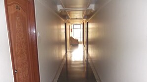 A long, narrow hallway with a wooden door on the left labeled "203". - Hotel Ravikant (Pune)