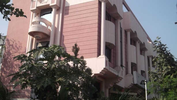 A multi-story building with a prominent pink facade and a sign in a local language. - Hotel Ravikant (Pune)