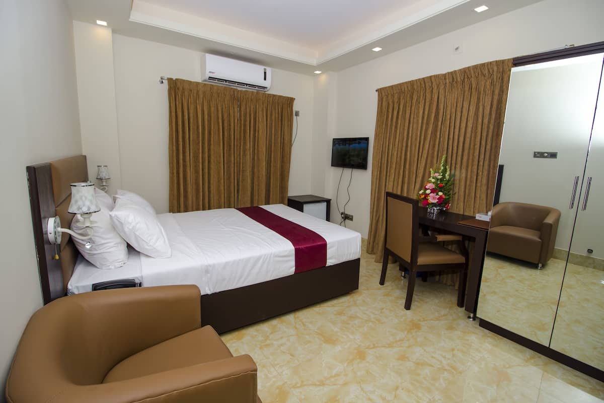 A hotel room with a bed, a desk, a chair, a TV, and a mirror.