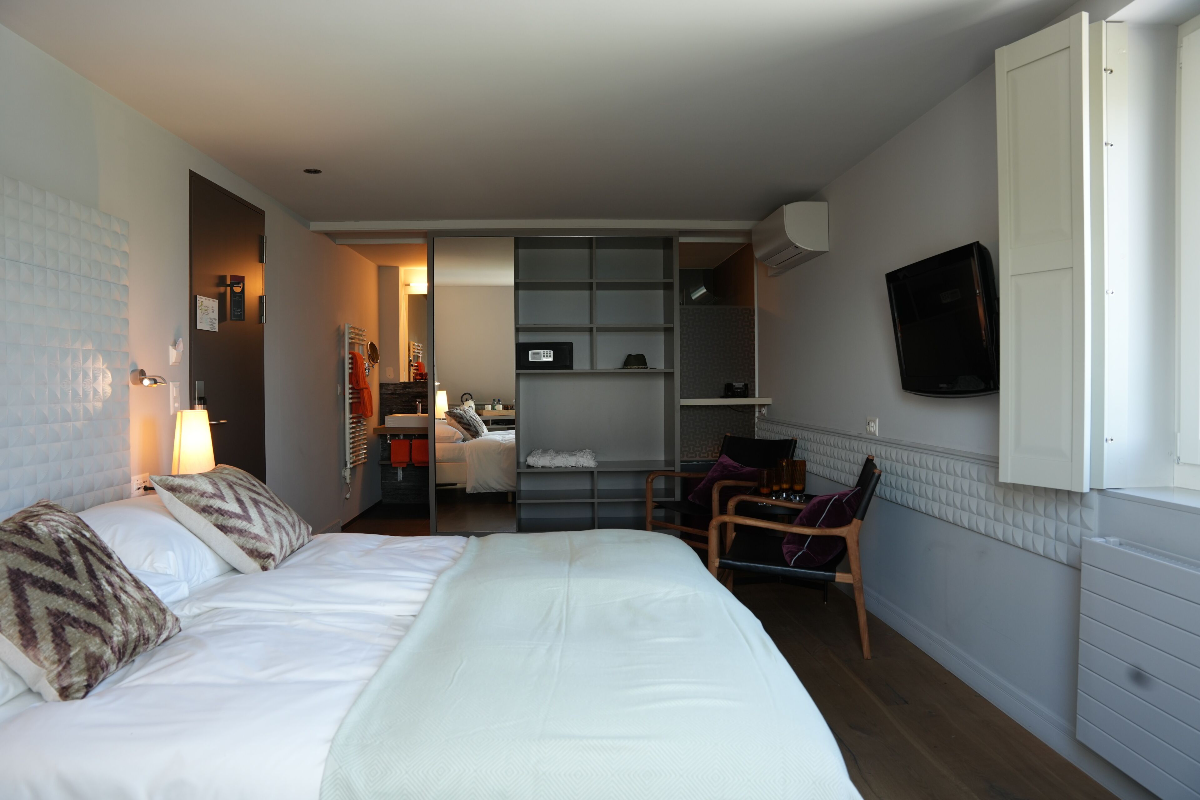Una habitación de hotel con cama, escritorio, silla, televisor y armario.