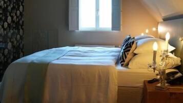Un dormitorio con una cama, una mesita de noche, una ventana y un techo inclinado.